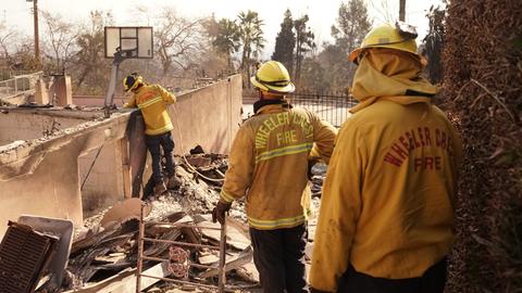 Los Angeles: Feuerwehrleute sind in dem von Waldbränden verwüsteten Gebiet von Altadena unterwegs. Sie stehen in den Trümmern eines Hauses. 