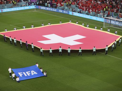Die Schweizer Flagge wird vor dem WM-Achtelfinale in Doha auf den Rasen in Lusail City getragen. 