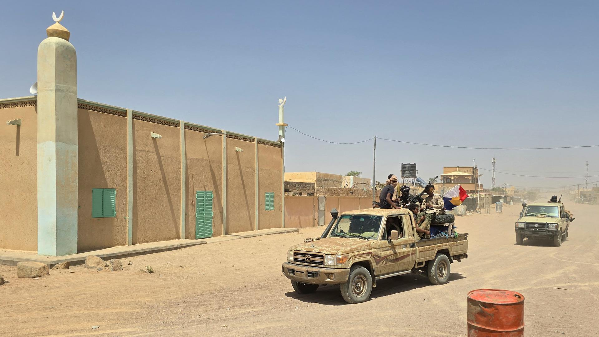 Tuareg-Rebellen fahren in einem Pick-up-Konvoi über staubige Straßen an einer Moschee in Kidal vorbei. Tuareg-Rebellen fahren in einem Pick-up-Konvoi über staubige Straßen an einer Moschee in Kidal vorbei.