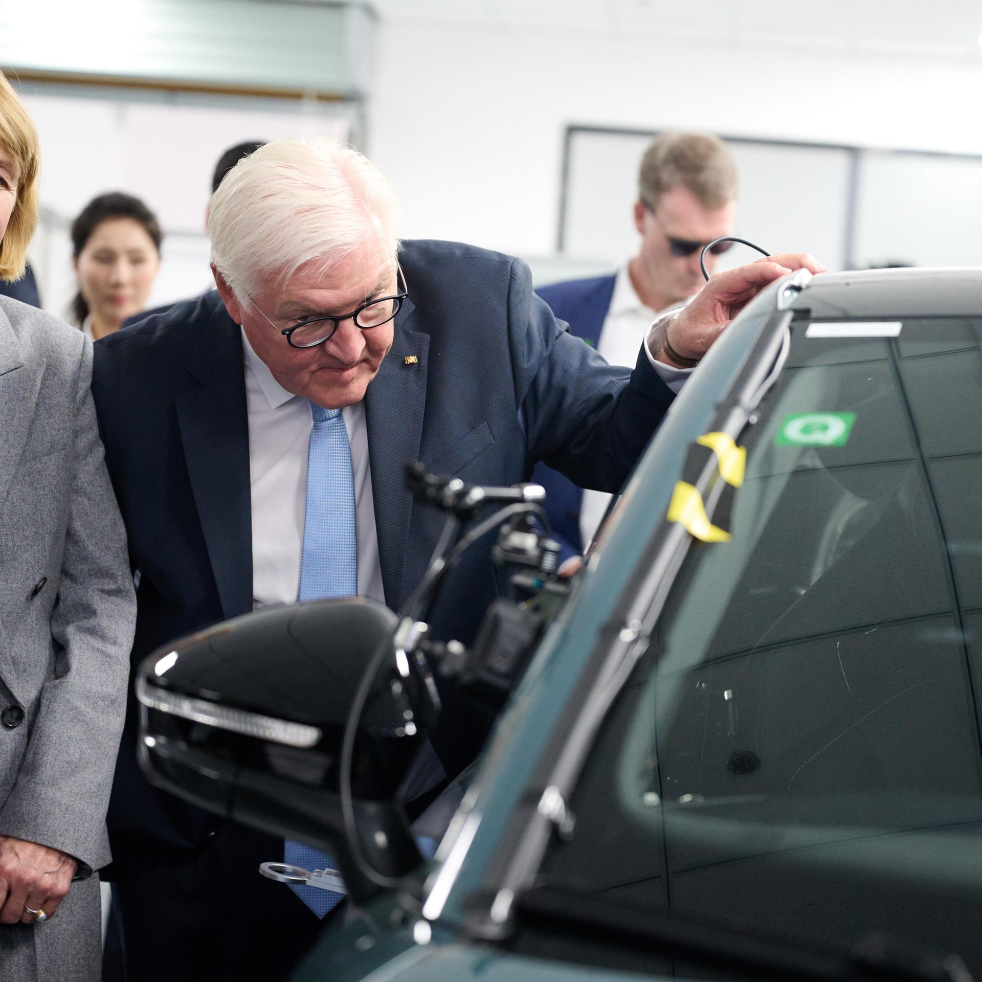 Bundespräsident Frank-Walter Steinmeier und seine Frau Elke Büdenbender besuchen einen Standort der Volkswagen Group China und schauen sich einen Volkswagen mit einem Roboterarm im Inneren an. 