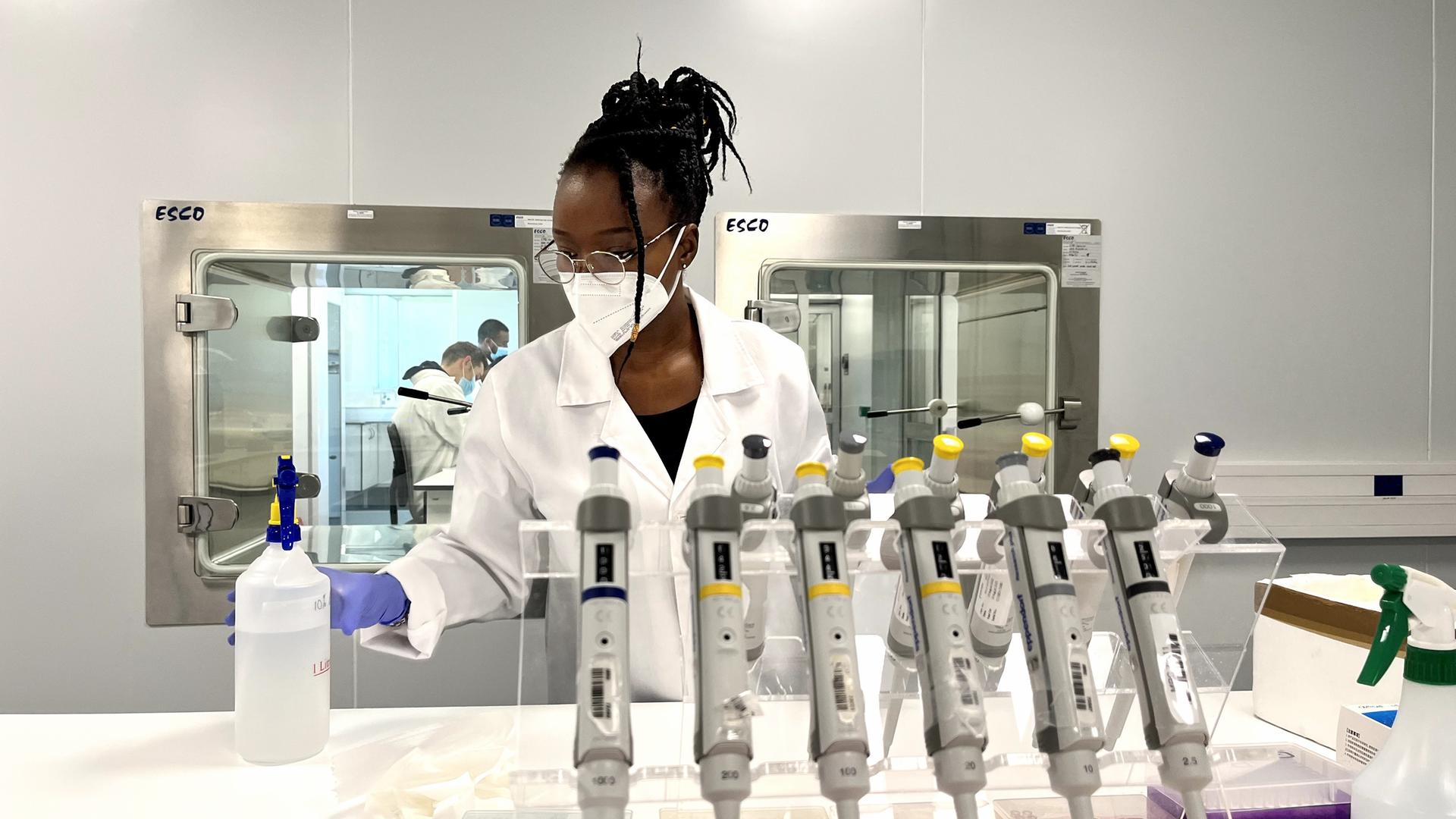 Eine Frau mit Mundschutz steht in einem chemischen Labor