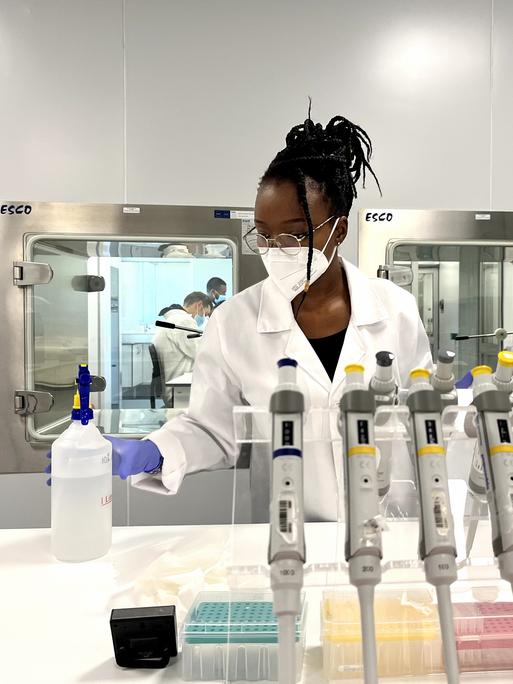 Eine Frau mit Mundschutz steht in einem chemischen Labor
