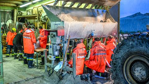 Einsatzkräfte der Feuerwehr und von dem Technisches Hilfswerk (THW) befüllen Sandsäcke. Der Landkreis Günzburg hat den Katastrophenfall ausgerufen.