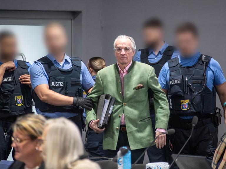 Heinrich XIII. Prinz Reuß (M), Hauptangeklagter im Prozess gegen eine mutmaßliche "Reichsbürger-Gruppe", wird von Justizbeamten in den Gerichtssaal geführt.