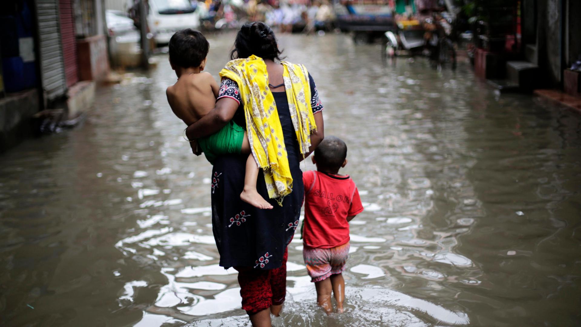 Eine Frau mit zwei Kindern bringt sich vor der Flut in Dhaka in Sicherheit