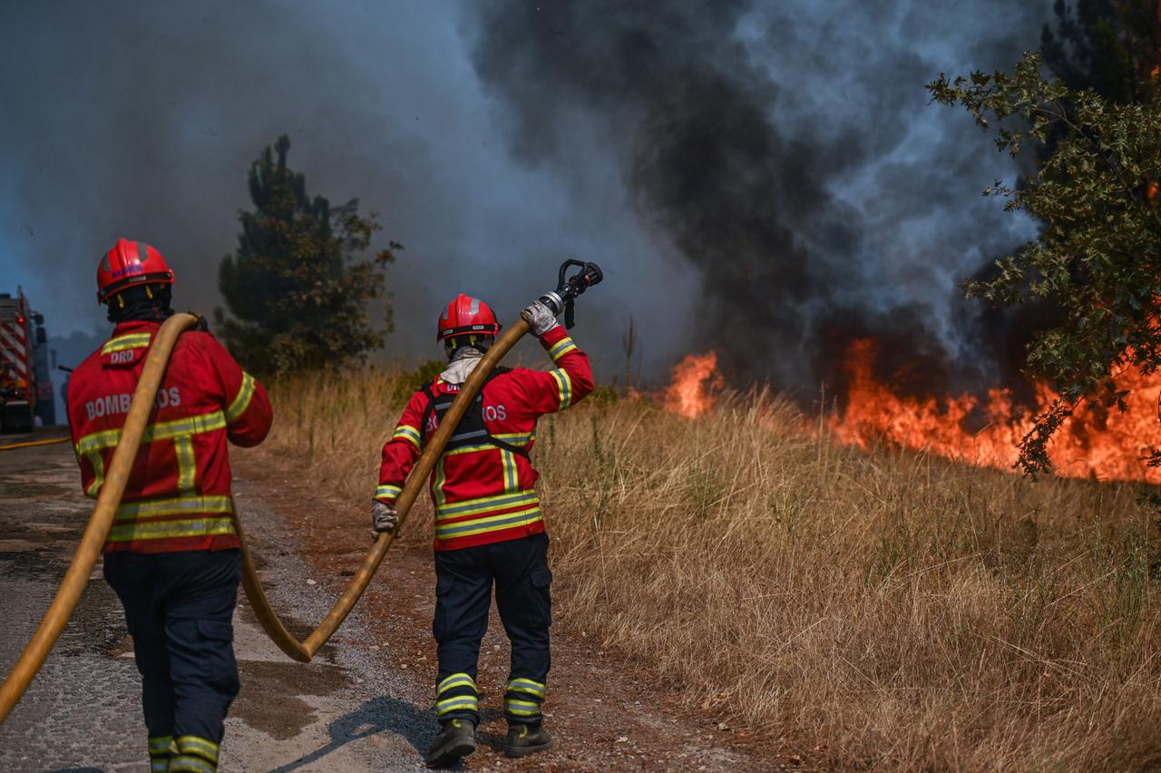 Feuerwehrleute versuchen am 22. August 2022 mit Wasserschläuchen einen Waldbrand bei Sao Tome do Castelo in Portugal einzudämmen. 