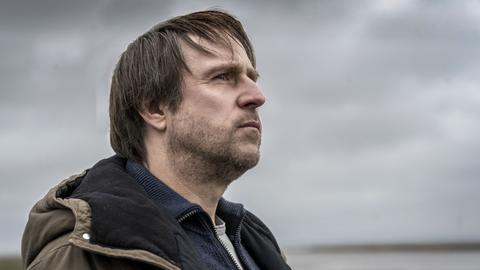 Bjarne Mädel blickt als Kommissar Sörensen an der Nordseeküste in die Weite.