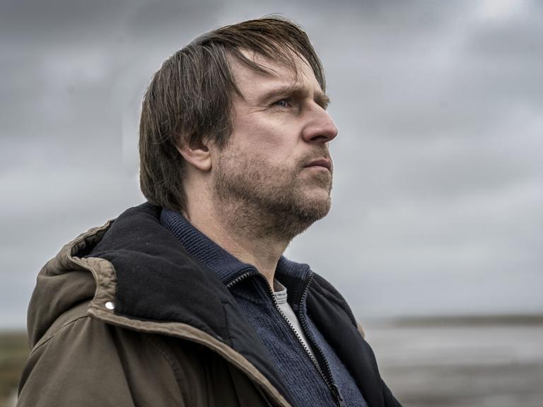 Bjarne Mädel blickt als Kommissar Sörensen an der Nordseeküste in die Weite.