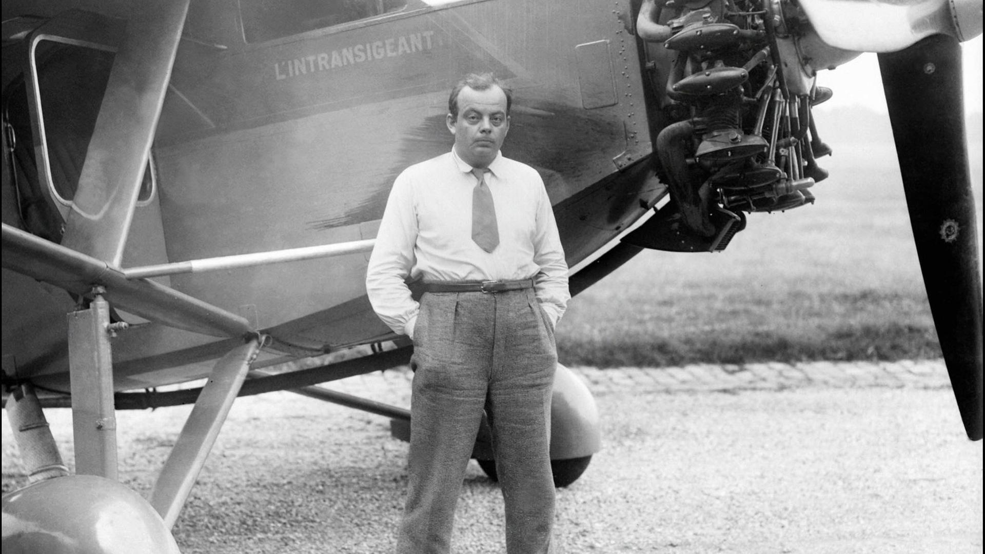 Der französische Autor und Pilot Antoine de Saint-Exupéry steht vor seinem Flugzeug, die Hände in den Hosentaschen.