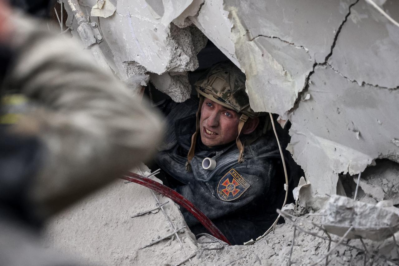 Rettungskräfte in Slowjansk suchen in den Trümmern nach Überlebenden. Man sieht das Gesicht eines Soldaten durch ein Loch in den Steinen schauen.