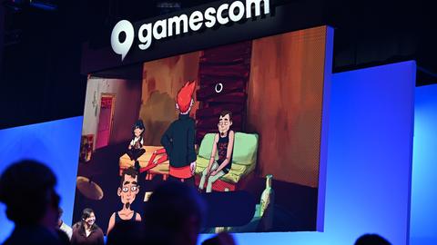 Bei der politischen Eröffnung der Gamescom blicken Zuschauer in Richtung Bühne, während auf einer Leinwand Szenen des Computerspiels "Grenzgänger" gezeigt werden. Bei der politischen Eröffnung der Gamescom blicken Zuschauer in Richtung Bühne, während auf einer Leinwand Szenen des Computerspiels "Grenzgänger" gezeigt werden.