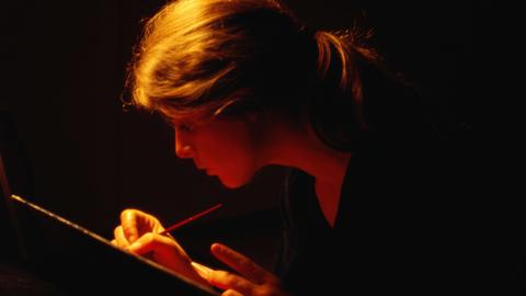 Eine Frau schreibt bei Dunkelheit. Eine Frau schreibt bei Dunkelheit.