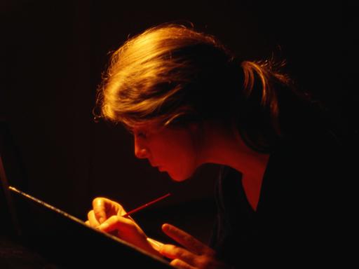 Eine Frau schreibt bei Dunkelheit.