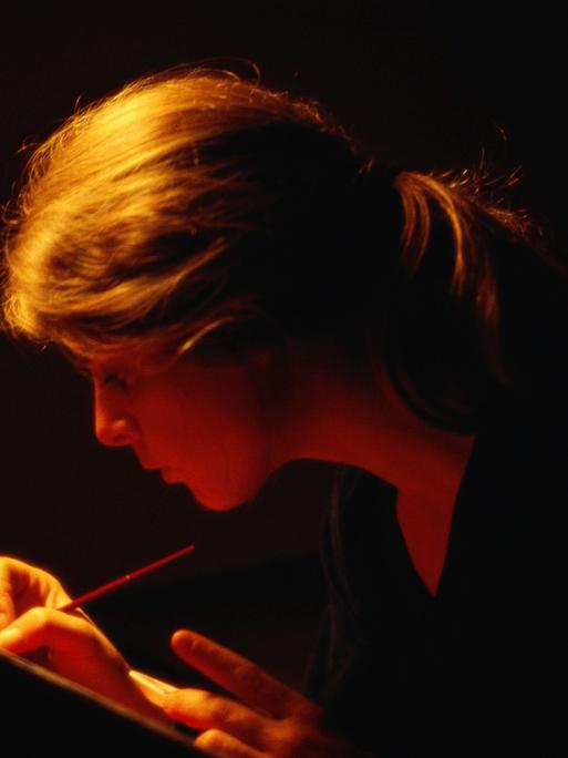 Eine Frau schreibt bei Dunkelheit. Eine Frau schreibt bei Dunkelheit.
