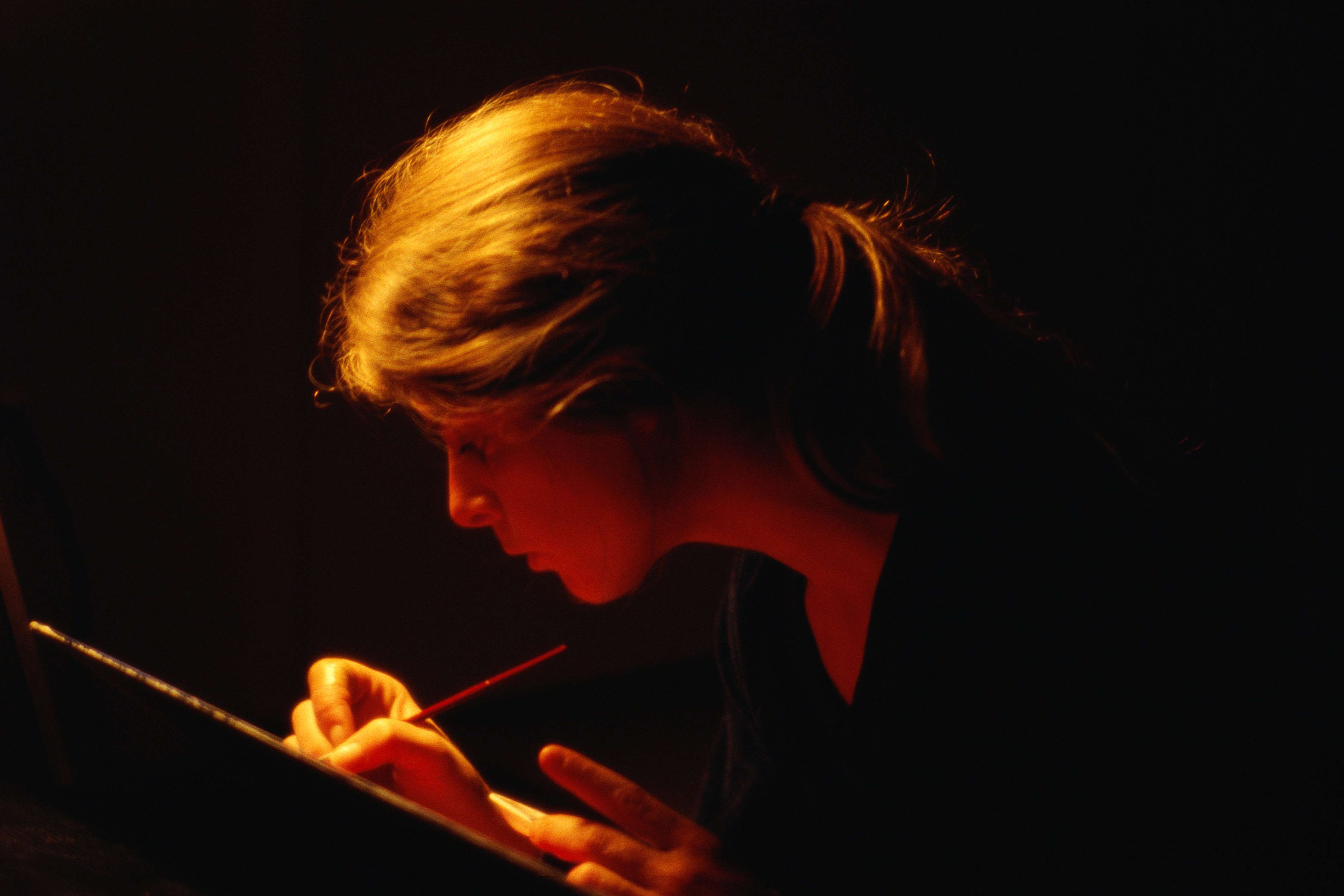 Eine Frau schreibt bei Dunkelheit.
