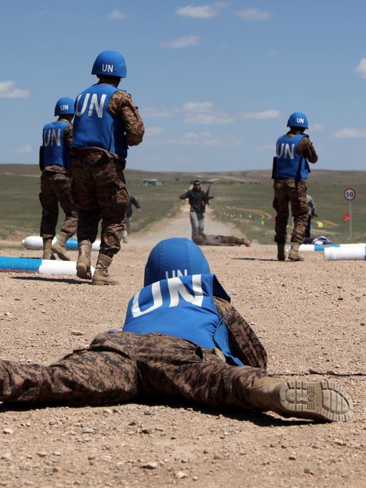 Blauhelmsodaten in der Mongolei üben in einer weiten staubigen Landschaft die Sicherung einer Straße.