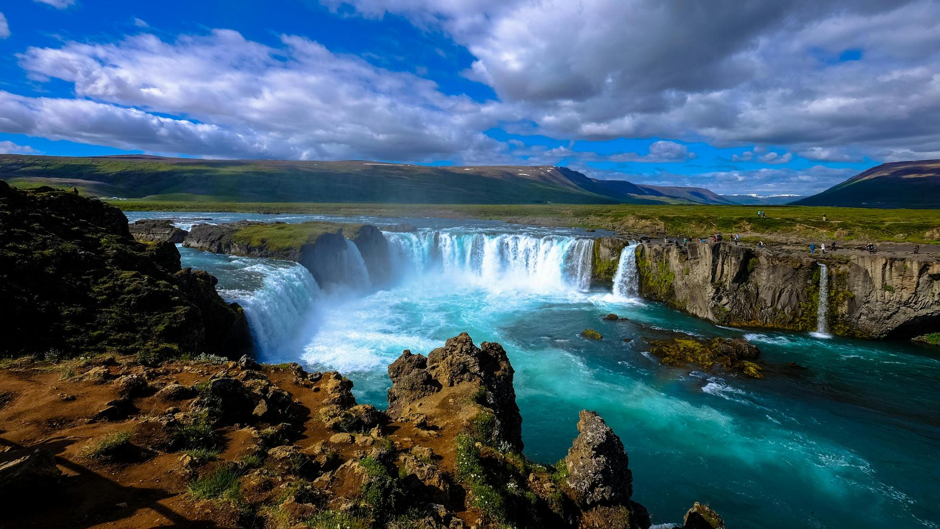 Blick auf einen großen isländischen Wasserfall mit blauem Himmel und wilden Wolken. Blick auf einen großen isländischen Wasserfall mit blauem Himmel und wilden Wolken.