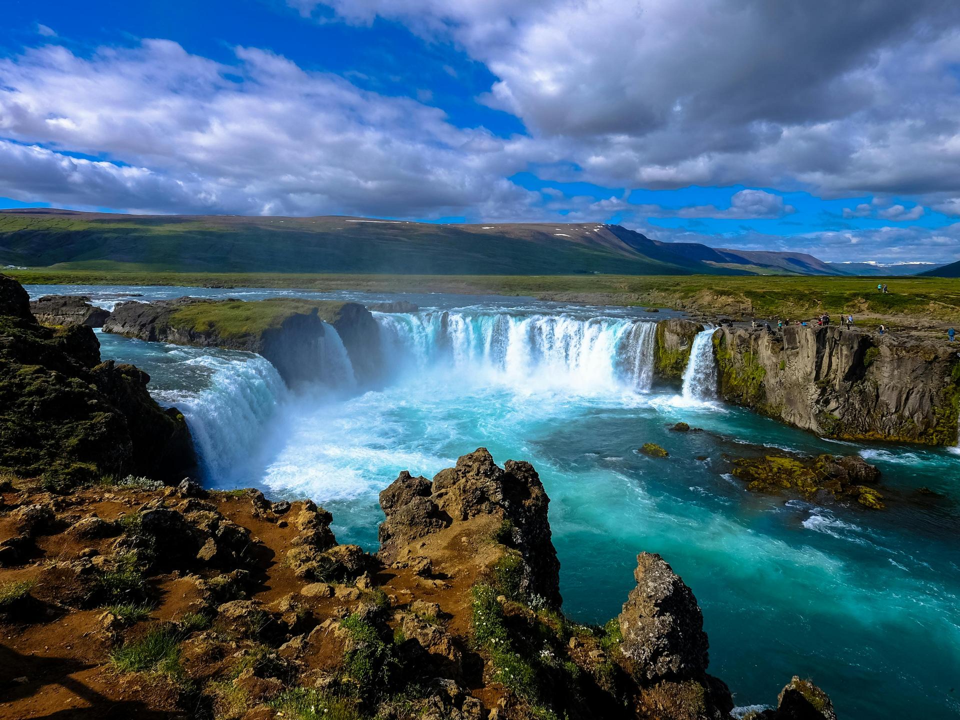Blick auf einen großen isländischen Wasserfall mit blauem Himmel und wilden Wolken. Blick auf einen großen isländischen Wasserfall mit blauem Himmel und wilden Wolken.