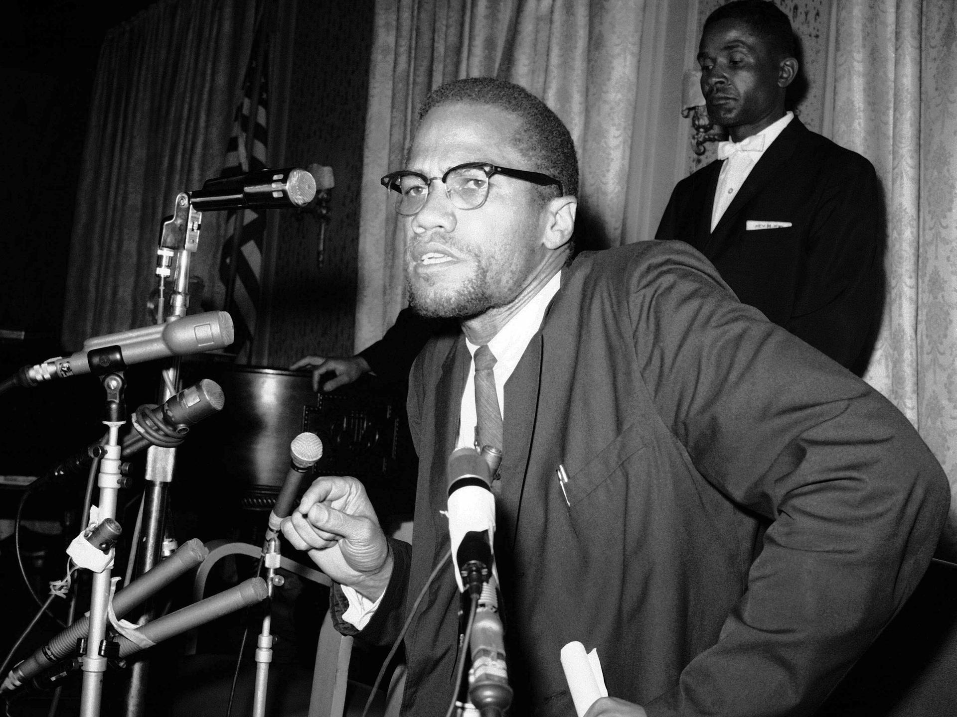 Malcolm X umringt von Mikrofonen bei einer Pressekonferenz im Jahr 1963.