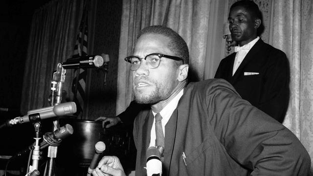 Malcolm X umringt von Mikrofonen bei einer Pressekonferenz im Jahr 1963.