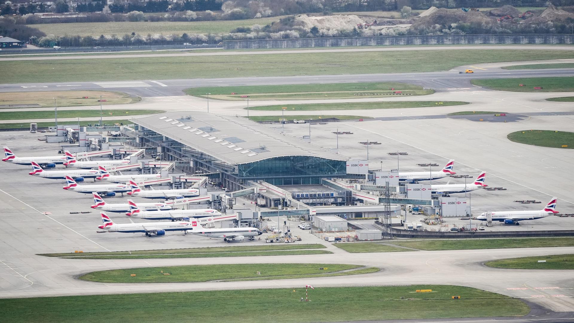 Luftaufnahme vom Flughafen Heathrow. Das Rollfeld ist leer, zahlreiche Flugzeuge stehen in den Parkbuchten.