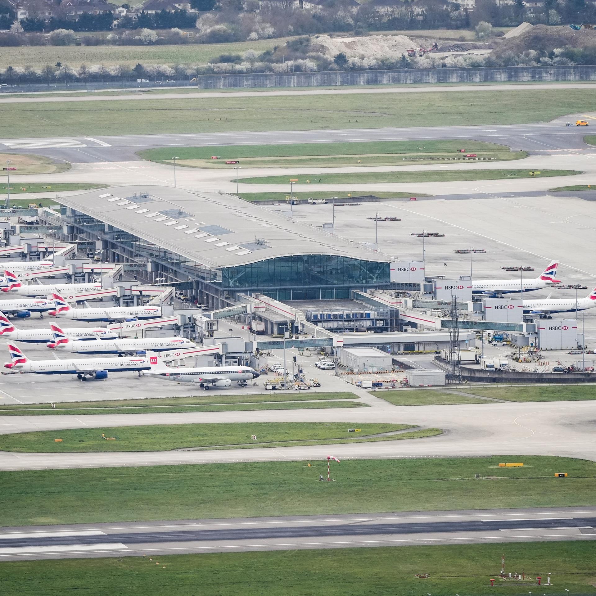 Luftaufnahme vom Flughafen Heathrow. Das Rollfeld ist leer, zahlreiche Flugzeuge stehen in den Parkbuchten.