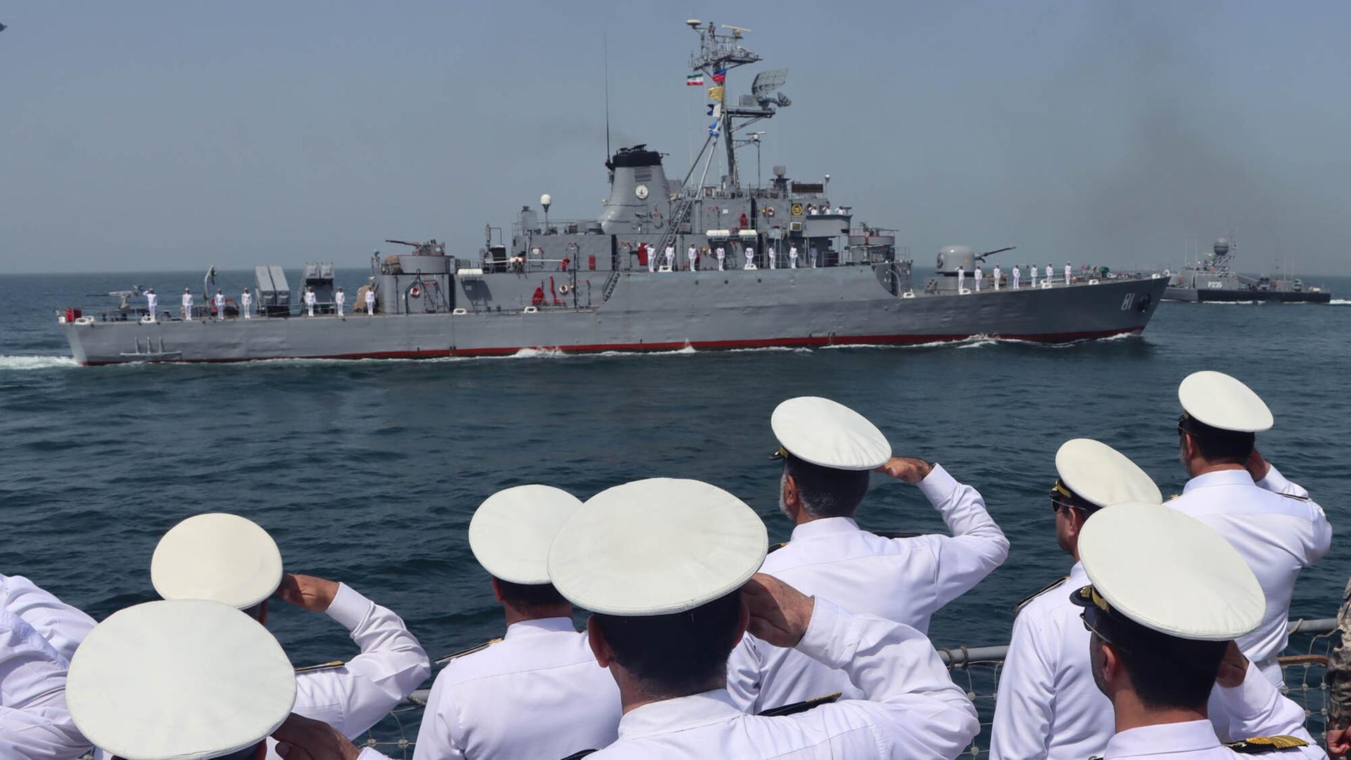 Ein Kriegsschiff bei einer gemeinsamen Übung von Iran, Russland und China im März 2024. Chinesische Soldaten salutieren davor an Land. 
