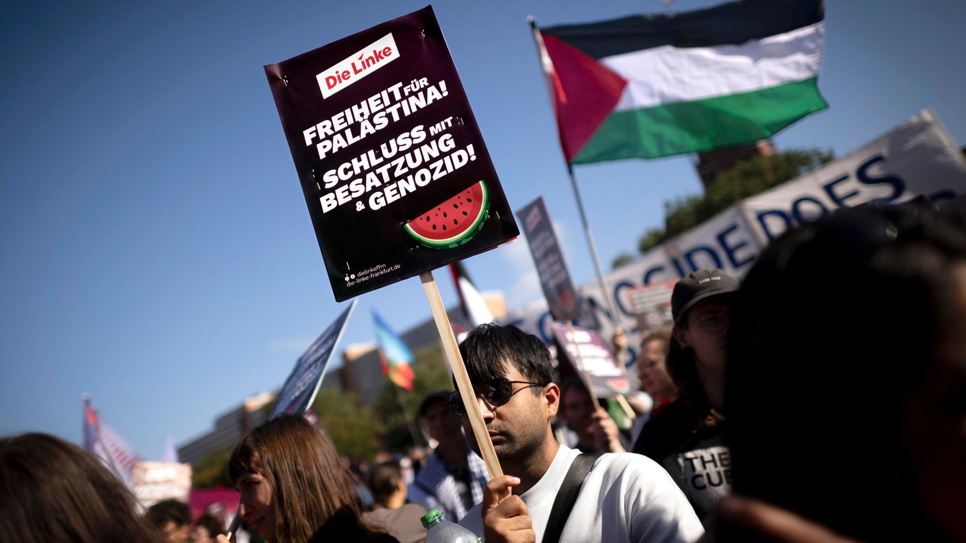 Ein Demonstrant hält ein Schild bei einer Demonstration hoch. Auf dem Schild steht: "Freiheit für Palästina - Schluss mit Besatzung und Genozid"