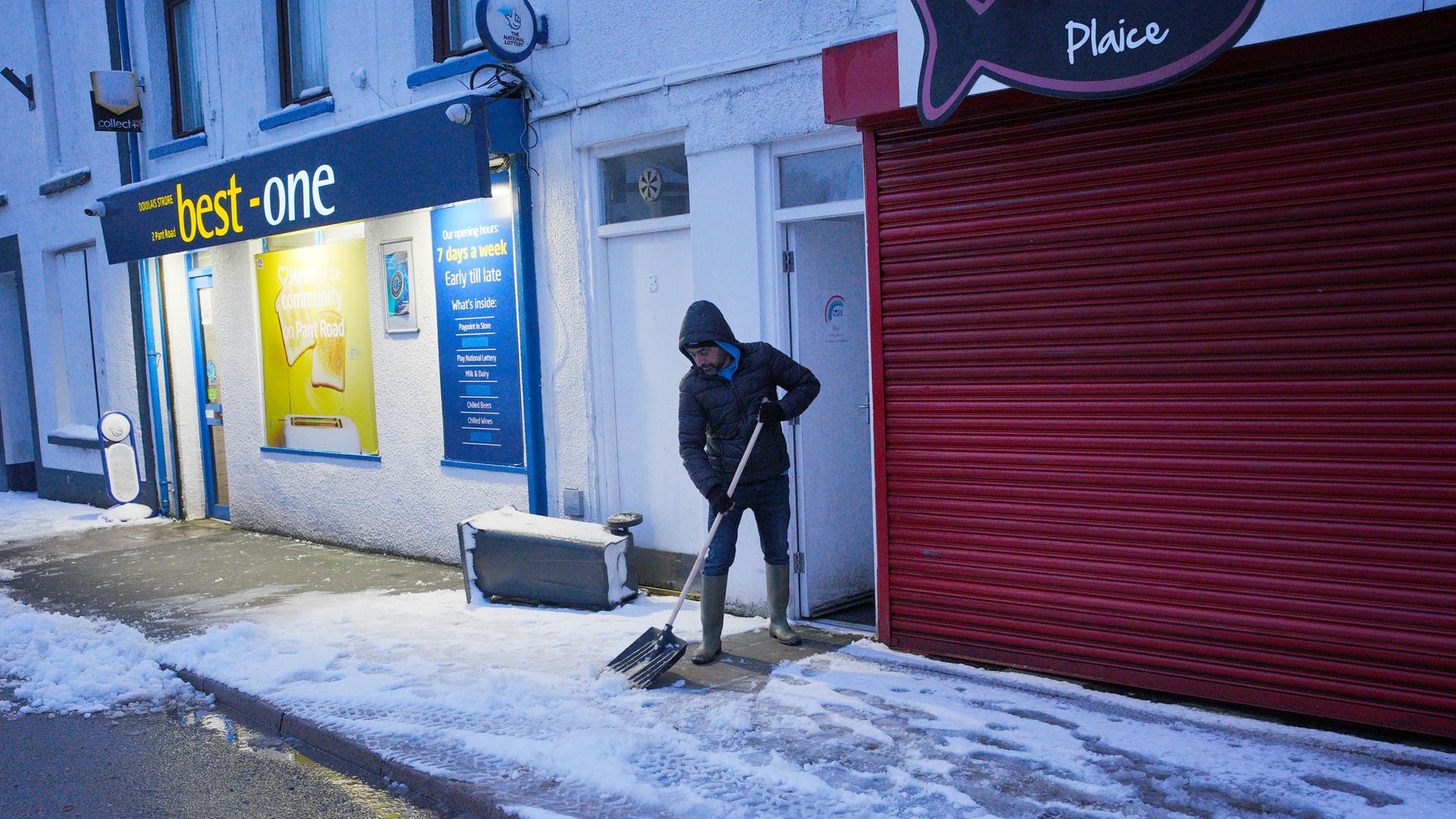 Großbritannien, Dowlais: Ein Mann räumt Schnee von einem Bürgersteig. Großbritannien, Dowlais: Ein Mann räumt Schnee von einem Bürgersteig.