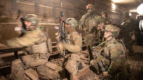 Rund ein halbes Dutzend Bundeswehrsoldaten in voller Montur bei einem Manöver in einem Berliner U-Bahn-Schacht.