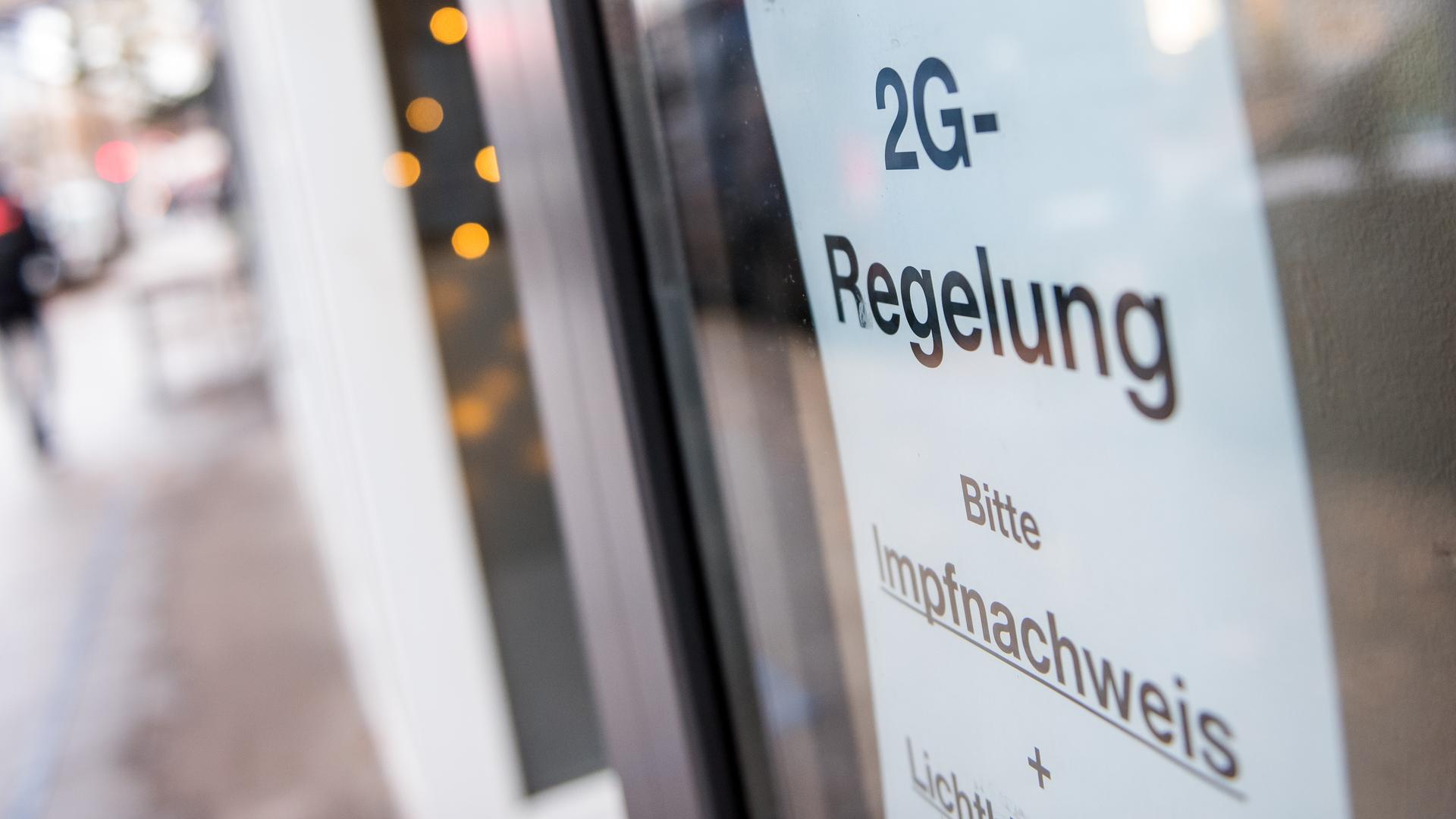Ein Schild mit der Aufschrift "2G-Regelung. Bitte Impfnachweis" hängt an dem Fenster von einem Lokal.