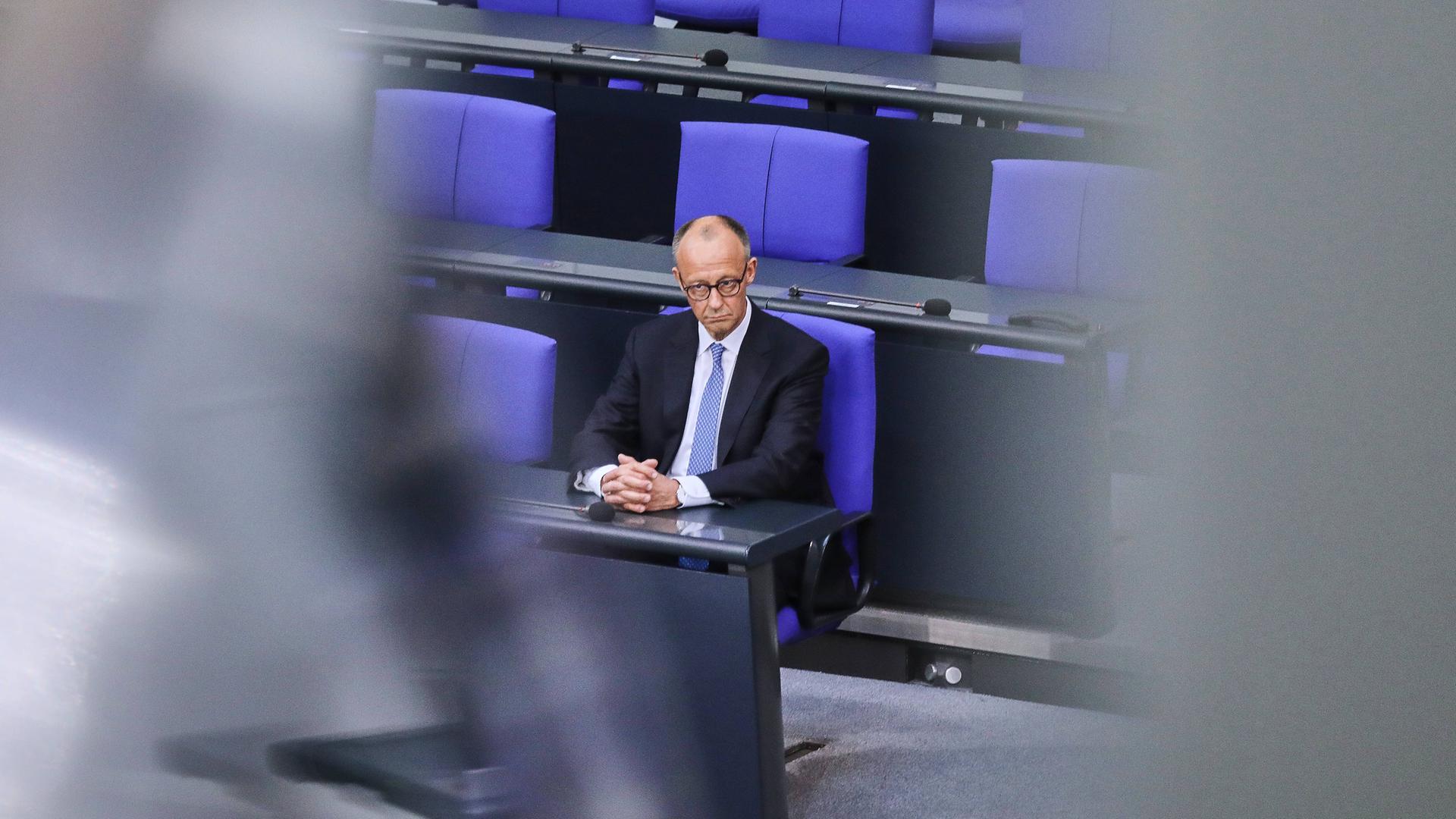 Bundeskanzler Friedrich Merz sitzt allein mit einem ernsten Gesicht auf einem blauen Stuhl im Bundestag. Bundeskanzler Friedrich Merz sitzt allein mit einem ernsten Gesicht auf einem blauen Stuhl im Bundestag.