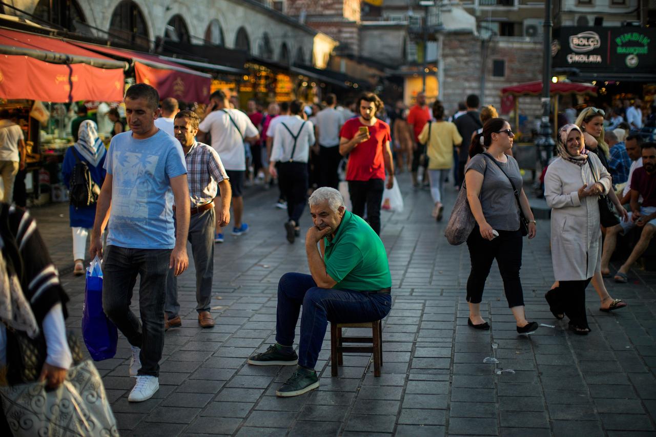 Ein älterer Mann sitzt inmitten einer Straße vor dem Ägyptischen Gewürzmarkt in Istanbul.