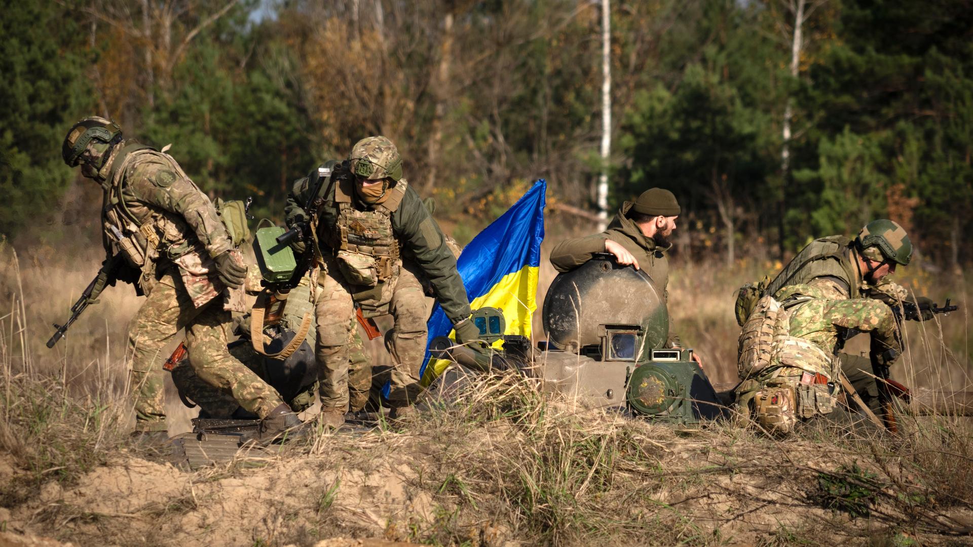Soldaten der 1. Brigade der ukrainischen Nationalgarde Bureviy (Hurricane) üben während der Gefechtsausbildung auf einem Truppenübungsplatz im Norden der Ukraine. In der Mitte eine ukrainische Nationalflagge.