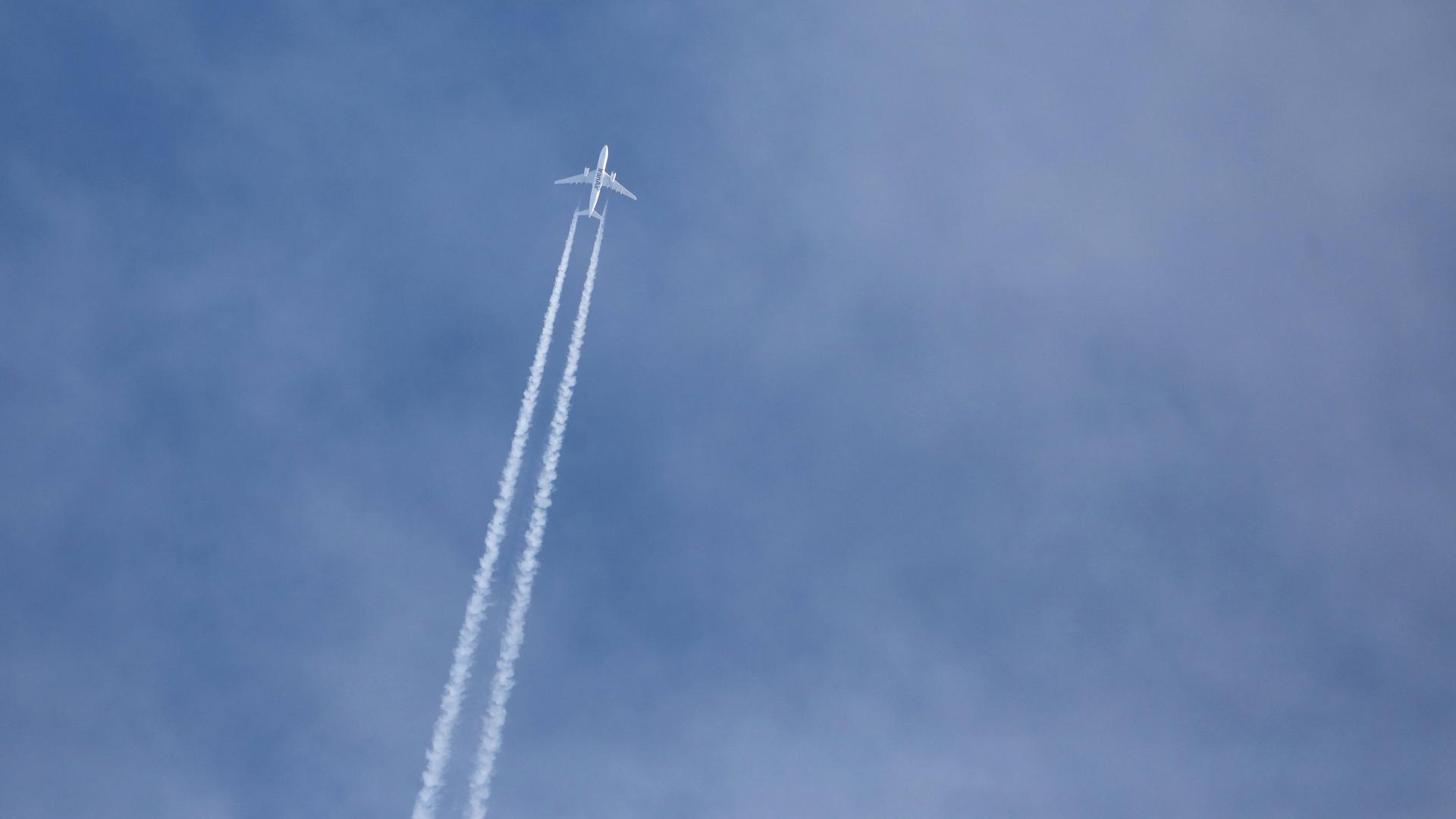 Ein Flugzeug bildet einen Kondensstreifen am Himmel.