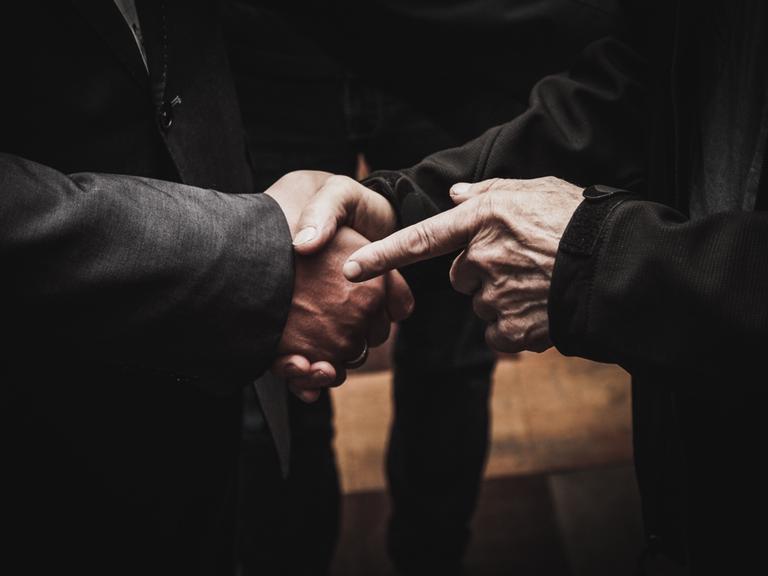 CLOSE-UP OF MAN HOLDING HANDS ON TABLE