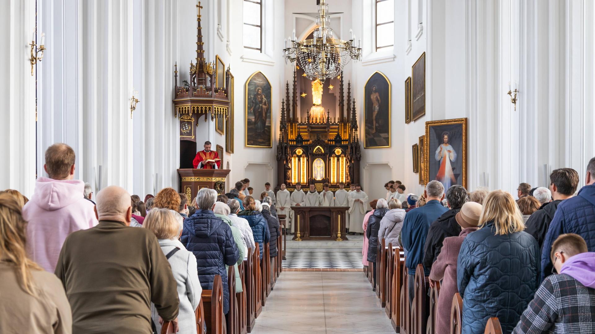 Gottesdienstbesucher stehen in der St.-Marien-Kirche in den Bankreihen und blicken zum Altar.