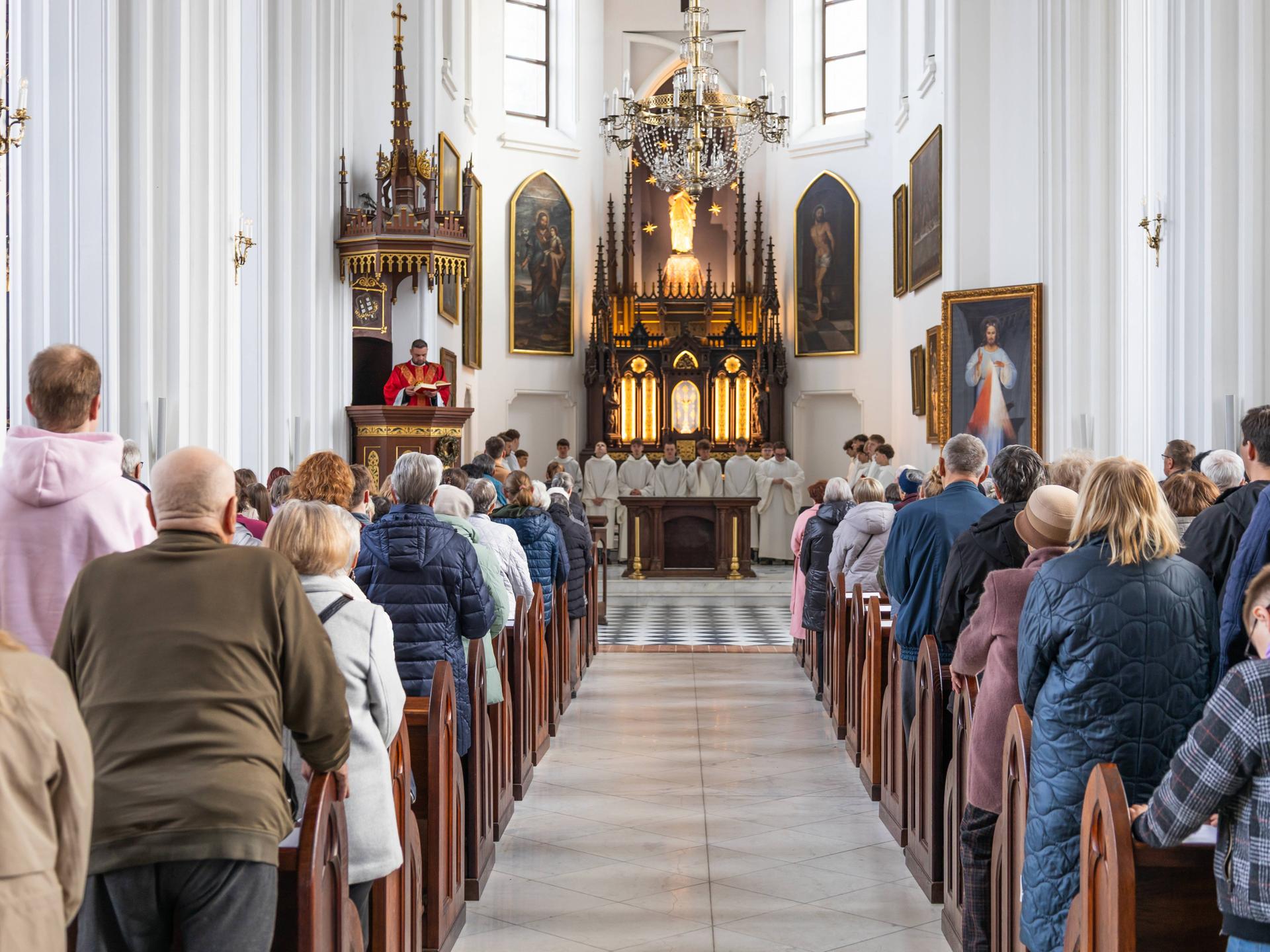 Gottesdienstbesucher stehen in der St.-Marien-Kirche in den Bankreihen und blicken zum Altar.