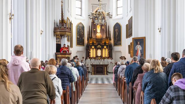 Gottesdienstbesucher stehen in der St.-Marien-Kirche in den Bankreihen und blicken zum Altar.