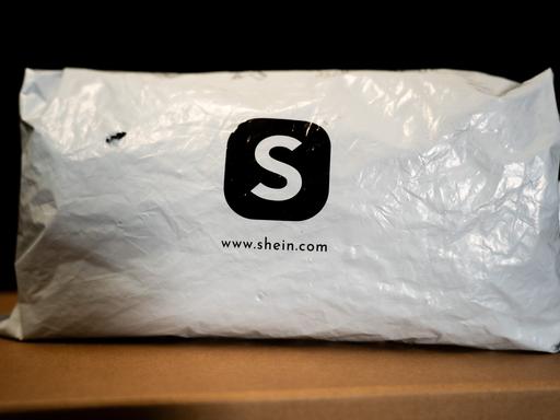 Ein weißes Versandpäckchen aus Kunststoff mit dem schwarzen Logo des Online-Händlers Shein.
