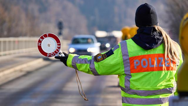 Polizistin stoppt den Verkehr mit einer Polizeikelle am Grenzübergang von Österreich nach Deutschland in Oberaudorf