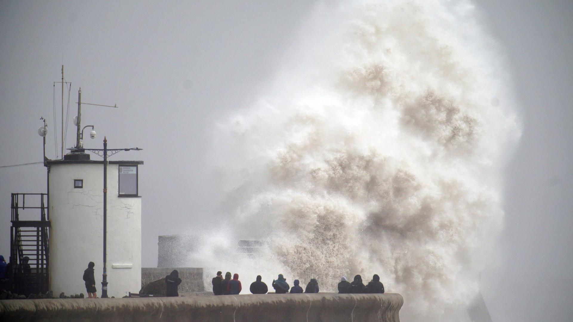 Schaulustige beobachten eine riesige Gischtwelle in Porthcawl in Wales.