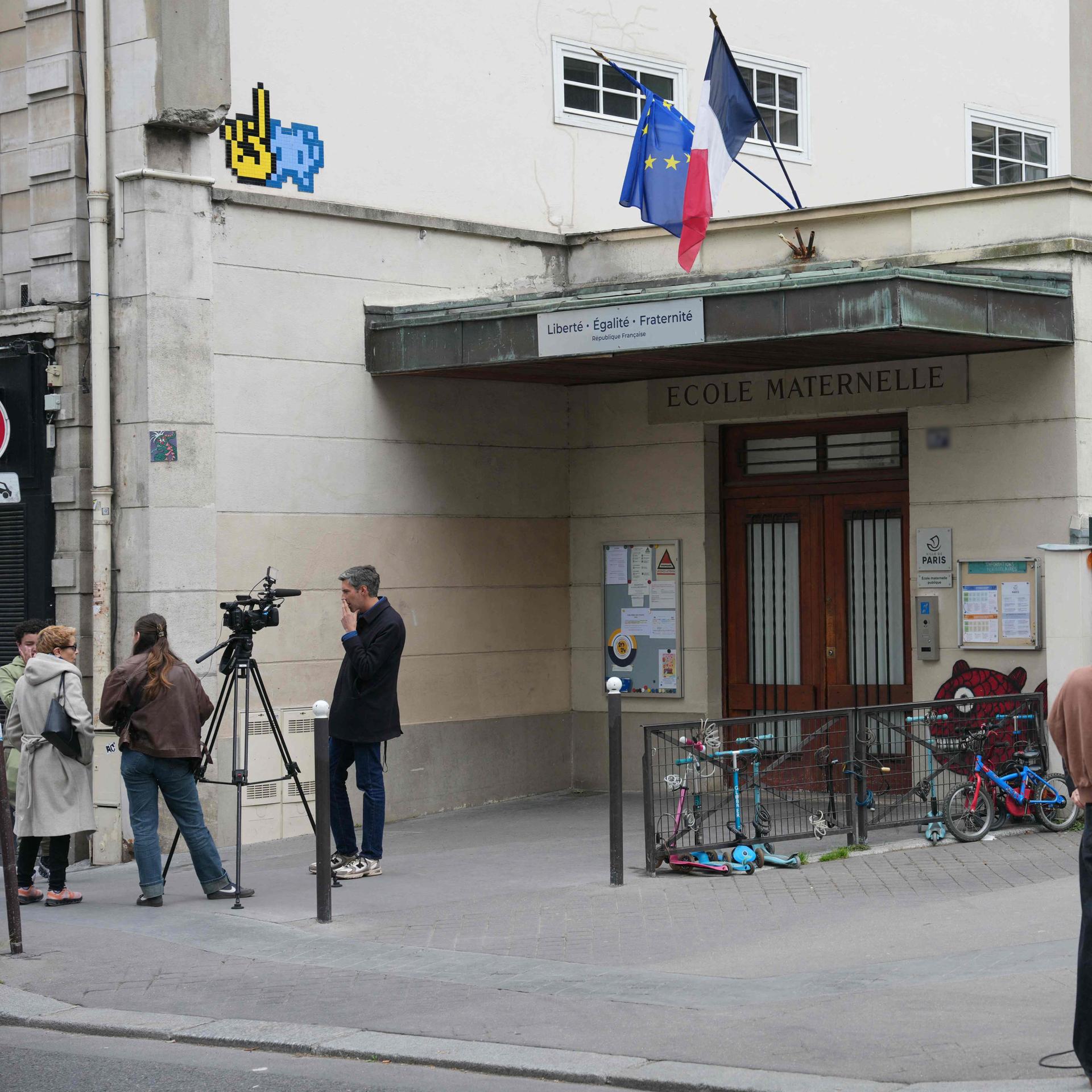 Journalisten stehen vor einem Kindergarten in Paris. 