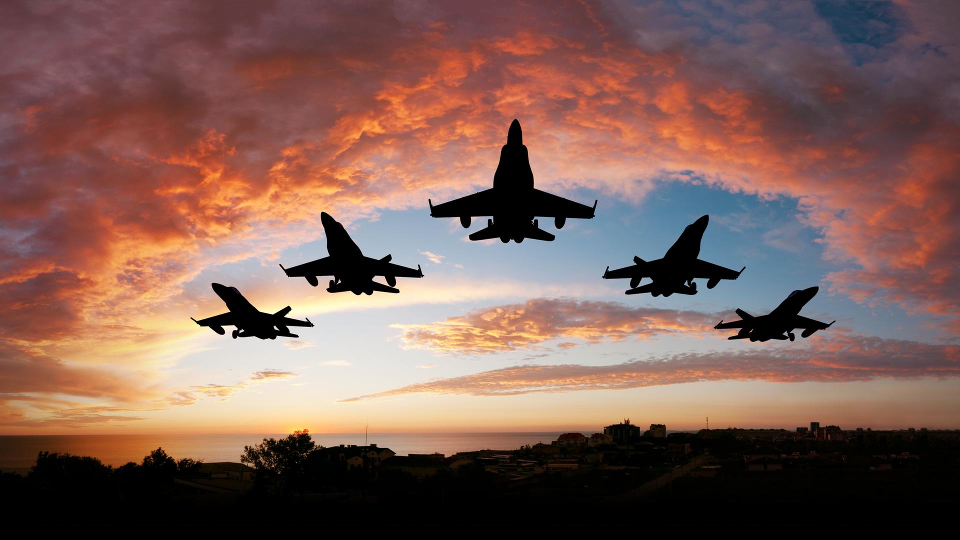 Fünf Kampfflugzeuge vor einem roten Abendhimmel
