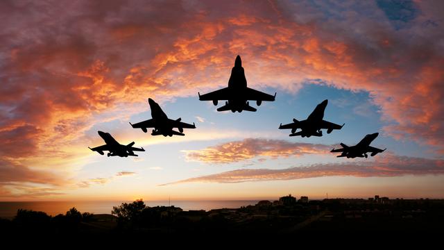 Fünf Kampfflugzeuge vor einem roten Abendhimmel