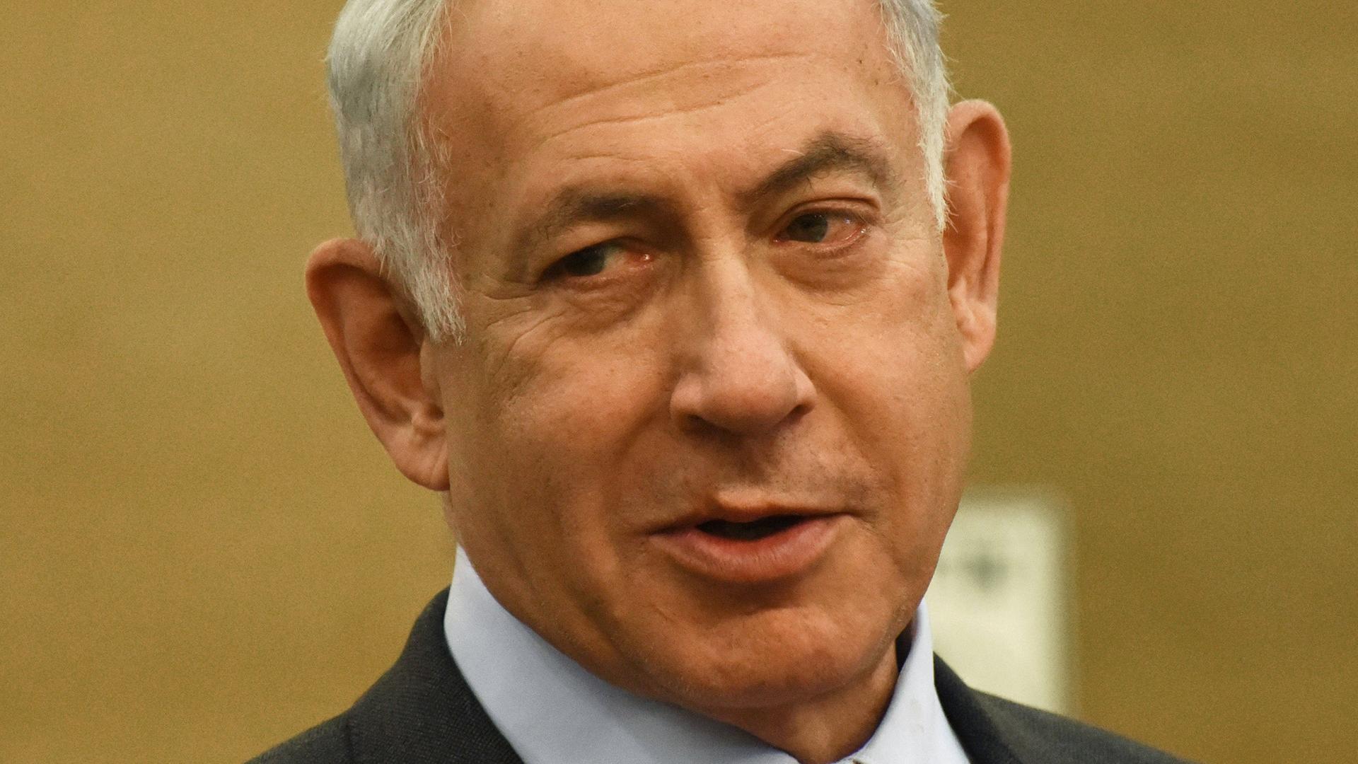Benjamin Netanjahu schaut vor einem beigen Hintergrund nach rechts unten