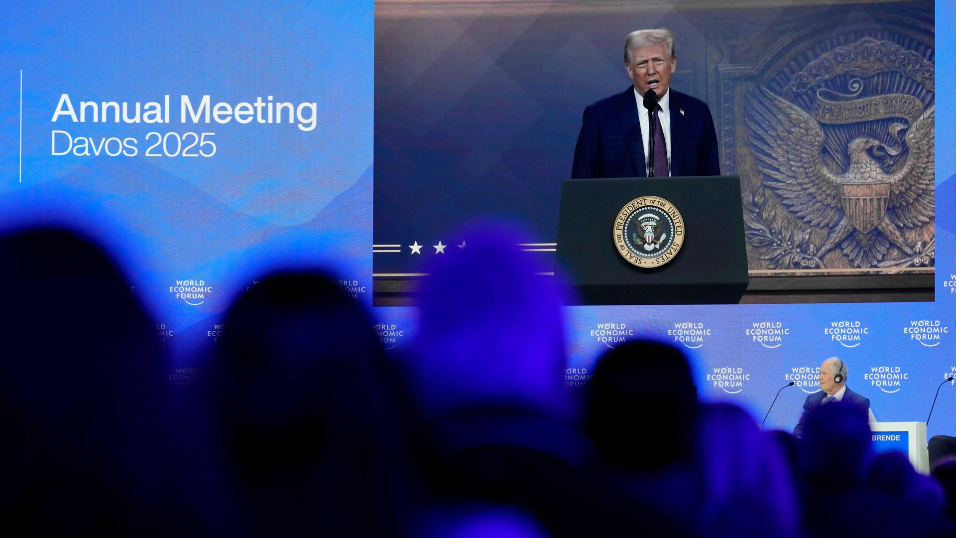 Besucher folgen auf dem Weltwirtschaftsforum der Rede von US-Präsident Donald Trump, der per Videoschalte in den Saal übertragen wird. 