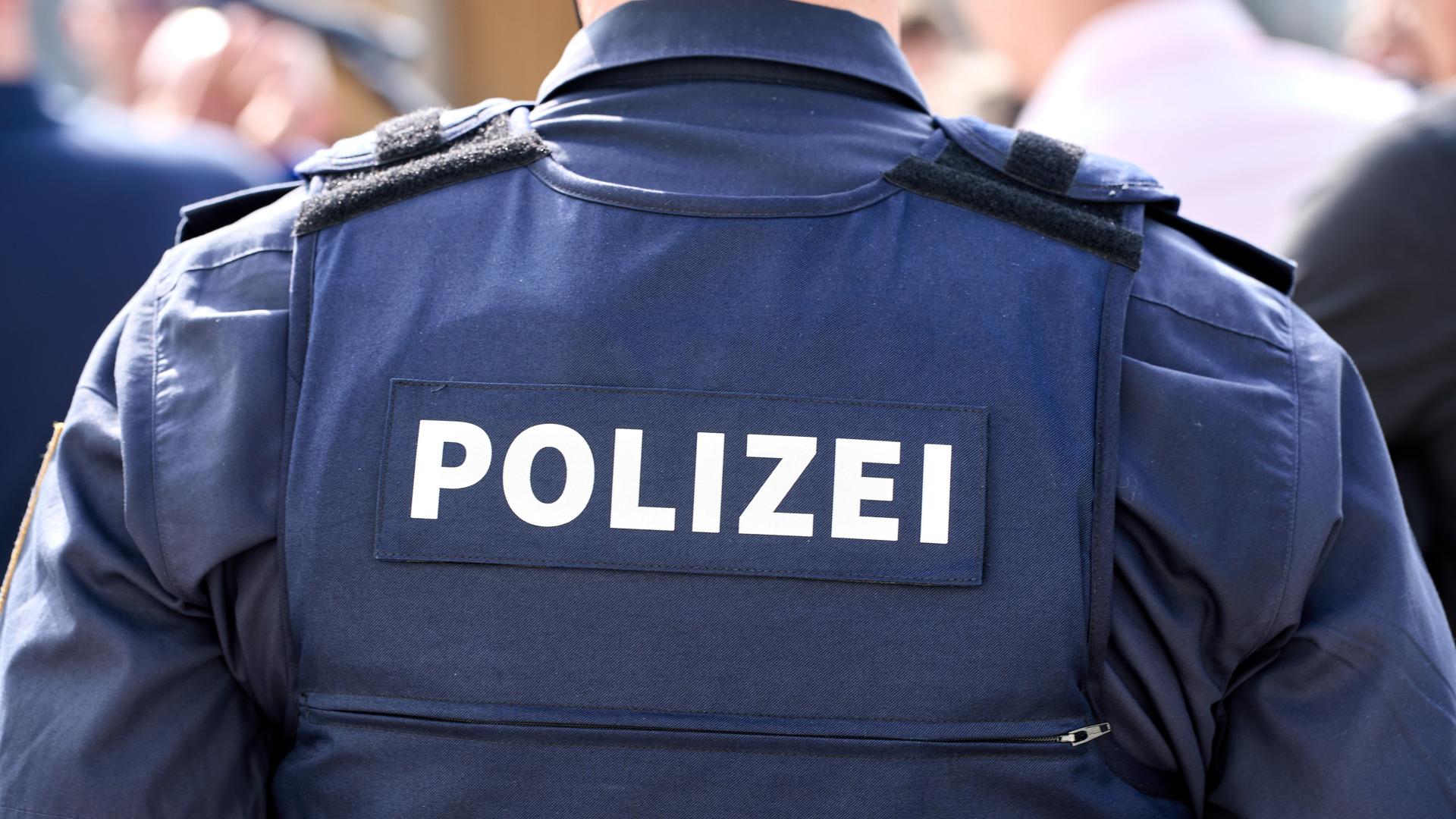 Polizist in Polizei Uniform vor einer Menschenmenge.