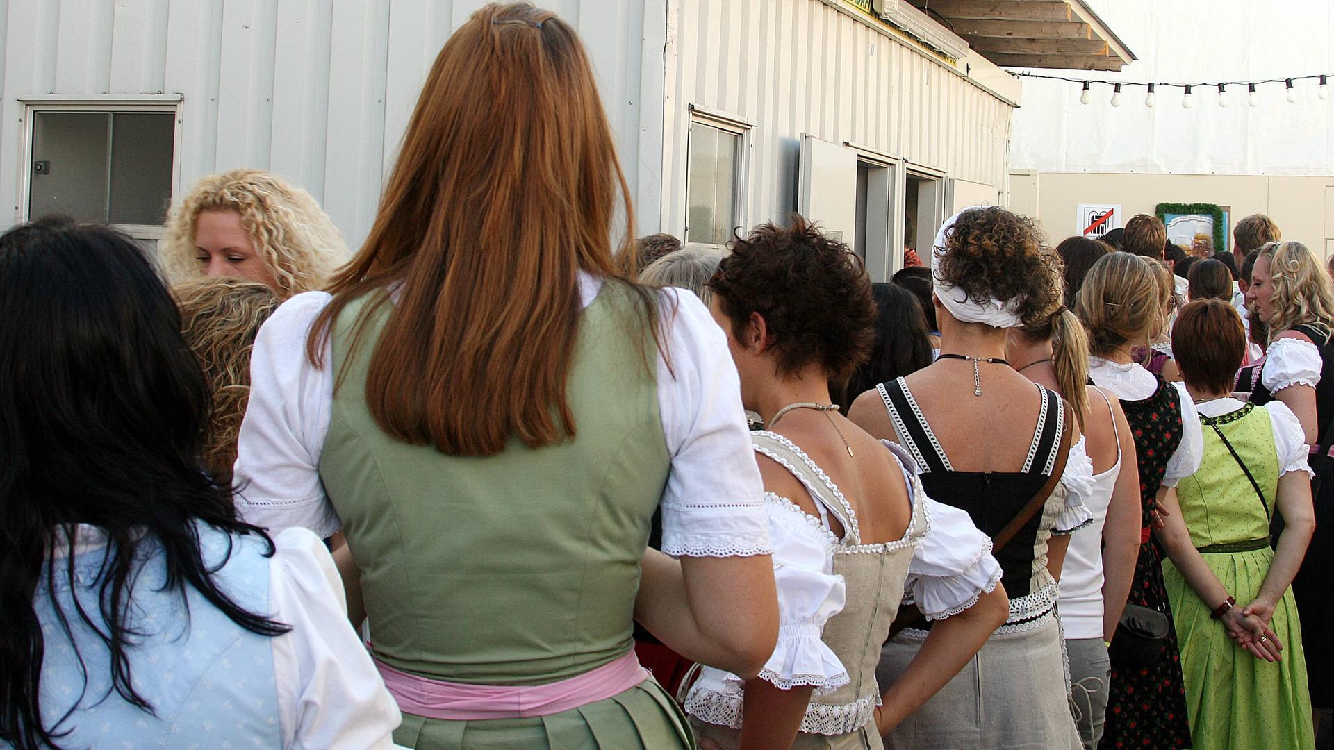 Frauen in einer Warteschlange an einer öffentlichen Toilette.