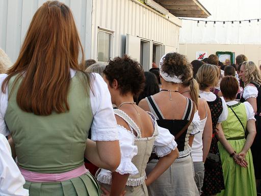 Frauen in einer Warteschlange an einer öffentlichen Toilette.